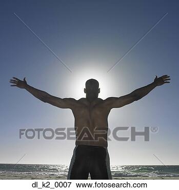 Picture - rear view of a 
young man standing 
on the beach with 
his arm. fotosearch 
- search stock 
photos, pictures, 
images, and photo 
clipart