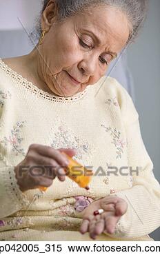 Stock Image - senior woman taking 
capsules from 
a bottle. fotosearch 
- search stock 
photos, pictures, 
images, and photo 
clipart