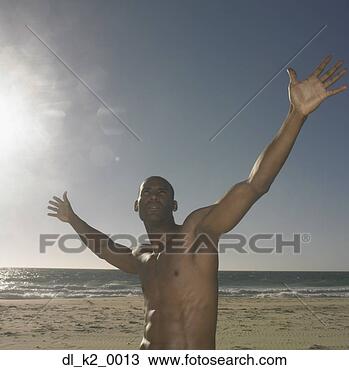 Stock Photo - young man standing 
on the beach with 
his arms outstretched. 
fotosearch - search 
stock photos, 
pictures, images, 
and photo clipart