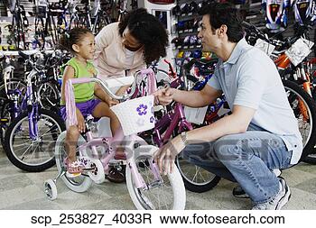Stock Photo - parents helping 
young daughter 
with bike in bike 
shop. fotosearch 
- search stock 
photos, pictures, 
images, and photo 
clipart