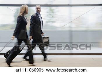 Stock Image - blurred businesspeople 
walking through 
airport terminal. 
fotosearch - search 
stock photos, 
pictures, images, 
and photo clipart