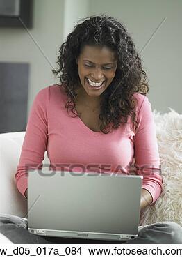 Stock Photo - african woman 
using laptop on 
sofa, toronto, 
canada. fotosearch 
- search stock 
photos, pictures, 
images, and photo 
clipart