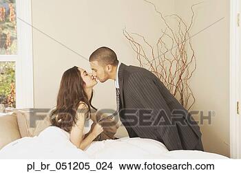 Stock Photo - hispanic man wearing 
a suit kissing 
hispanic woman 
sitting in bed. 
fotosearch - search 
stock photos, 
pictures, images, 
and photo clipart