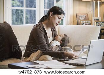 Stock Photo - hispanic woman 
paying bills online 
with sleeping 
baby. fotosearch 
- search stock 
photos, pictures, 
images, and photo 
clipart