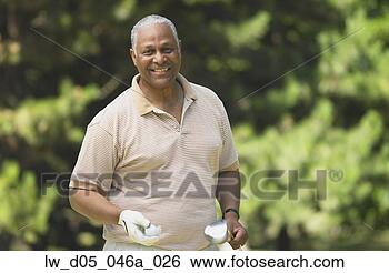 Stock Photo - middle-aged african 
man holding golf 
club and ball, 
toronto, canada. 
fotosearch - search 
stock photos, 
pictures, images, 
and photo clipart