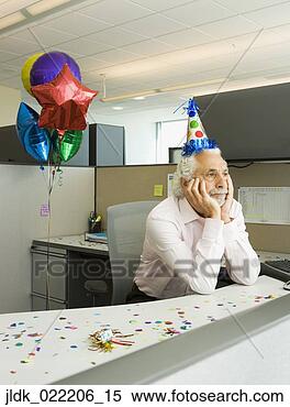 Stock Image - senior businessman 
looking sad in 
a cubicle with 
a party hat and 
a. fotosearch 
- search stock 
photos, pictures, 
images, and photo 
clipart