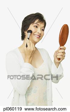 Stock Photograph - studio shot of 
middle-aged asian 
woman putting 
on make up. fotosearch 
- search stock 
photos, pictures, 
images, and photo 
clipart