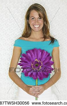 Stock Photo - young woman smiling 
and holding large 
flower. fotosearch 
- search stock 
photos, pictures, 
images, and photo 
clipart