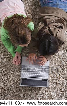 Picture - high angle view 
of two girls using 
laptop on the 
floor. fotosearch 
- search stock 
photos, pictures, 
images, and photo 
clipart