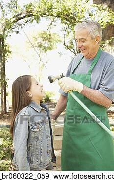 Stock Photograph - hispanic grandfather 
and granddaughter 
playing with hose. 
fotosearch - search 
stock photos, 
pictures, images, 
and photo clipart