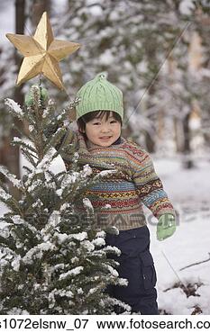 Picture - young asian girl 
with christmas 
tree in snow outdoors. 
fotosearch - search 
stock photos, 
pictures, images, 
and photo clipart