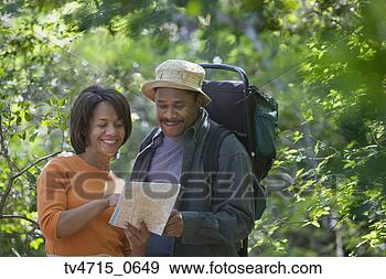 Stock Photograph - african couple 
hiking with map 
in woods. fotosearch 
- search stock 
photos, pictures, 
images, and photo 
clipart