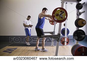 Picture - male personal 
trainer with male 
client lifting 
weights. fotosearch 
- search stock 
photos, pictures, 
images, and photo 
clipart