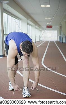 Stock Photo - man tying shoe 
on indoor track. 
fotosearch - search 
stock photos, 
pictures, images, 
and photo clipart