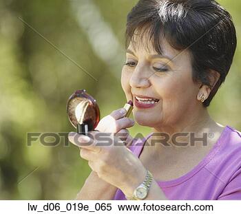 Banco de Imagem - middle-aged, hispânico, 
mulher, aplicando, 
batom, ao ar livre. 
fotosearch - busca 
de fotos, imagens 
e clipart
