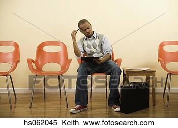 Stock Photo - african man filling 
out form in waiting 
area. fotosearch 
- search stock 
photos, pictures, 
images, and photo 
clipart