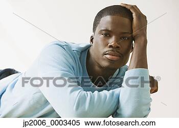 Stock Image - african man laying 
on floor leaning 
head on hand. 
fotosearch - search 
stock photos, 
pictures, images, 
and photo clipart
