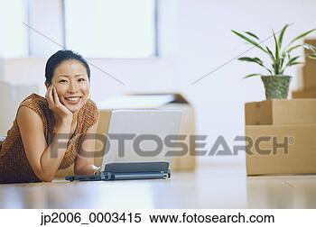 Stock Image - asian woman using 
laptop in new 
house with boxes. 
fotosearch - search 
stock photos, 
pictures, images, 
and photo clipart