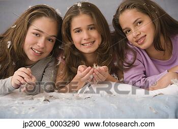 Stock Photography - hispanic sisters 
laying on bed 
with down feathers. 
fotosearch - search 
stock photos, 
pictures, images, 
and photo clipart