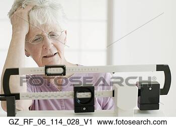 Stock Photography - senior woman weighing 
self on scale. 
fotosearch - search 
stock photos, 
pictures, images, 
and photo clipart