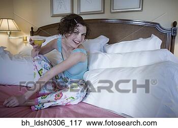 Picture - woman sitting 
on bed with cocktail. 
fotosearch - search 
stock photos, 
pictures, images, 
and photo clipart