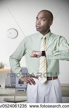 Stock Image - african businessman 
holding up watch 
and frowning. 
fotosearch - search 
stock photos, 
pictures, images, 
and photo clipart