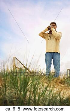 Stock Photo - man standing on 
sand dune taking 
photograph. fotosearch 
- search stock 
photos, pictures, 
images, and photo 
clipart