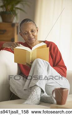 Stock Photo - senior african 
woman reading 
on sofa. fotosearch 
- search stock 
photos, pictures, 
images, and photo 
clipart