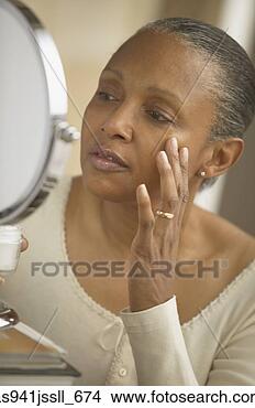 Stock Photo - senior african 
woman touching 
face and looking 
in mirror. fotosearch 
- search stock 
photos, pictures, 
images, and photo 
clipart