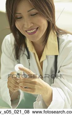 Stock Photo - asian female doctor 
looking at medication. 
fotosearch - search 
stock photos, 
pictures, images, 
and photo clipart