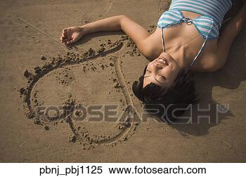Stock Image - asian woman laying 
next to heart 
drawn in sand. 
fotosearch - search 
stock photos, 
pictures, images, 
and photo clipart