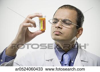 Stock Photo - indian male pharmacist 
looking at medication 
bottle. fotosearch 
- search stock 
photos, pictures, 
images, and photo 
clipart