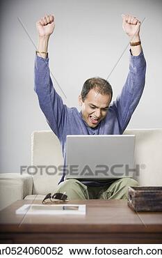 Stock Photo - indian man cheering 
on sofa with laptop. 
fotosearch - search 
stock photos, 
pictures, images, 
and photo clipart