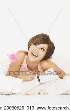Stock Photograph - woman laying on 
bed writing in 
journal. fotosearch 
- search stock 
photos, pictures, 
images, and photo 
clipart