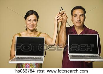 Stock Photo - hispanic couple 
holding cable 
connecting two 
laptops. fotosearch 
- search stock 
photos, pictures, 
images, and photo 
clipart