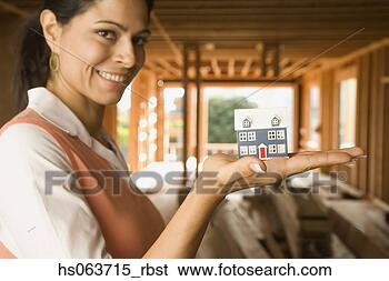 Stock Photo - hispanic woman 
holding model 
house at construction 
site. fotosearch 
- search stock 
photos, pictures, 
images, and photo 
clipart