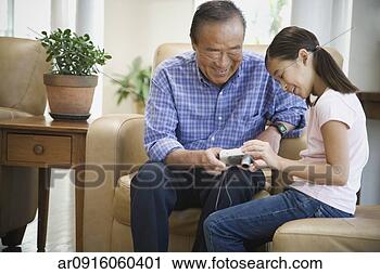 Stock Photography - asian grandfather 
and granddaughter 
looking at digital 
camera. fotosearch 
- search stock 
photos, pictures, 
images, and photo 
clipart