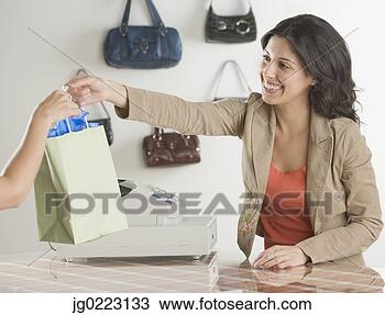 Stock Photo - hispanic clerk 
handing purchase 
to customer at 
boutique. fotosearch 
- search stock 
photos, pictures, 
images, and photo 
clipart