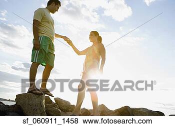 Stock Photo - hispanic couple 
holding hands 
on rocks at beach. 
fotosearch - search 
stock photos, 
pictures, images, 
and photo clipart