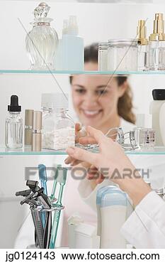 Stock Photo - hispanic woman 
reaching into 
medicine cabinet. 
fotosearch - search 
stock photos, 
pictures, images, 
and photo clipart