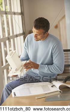 Stock Photography - male architect 
sitting on table 
looking at model 
of building. fotosearch 
- search stock 
photos, pictures, 
images, and photo 
clipart