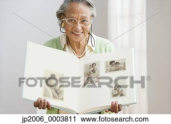 Stock Photography - senior african 
woman holding 
photo album. fotosearch 
- search stock 
photos, pictures, 
images, and photo 
clipart