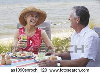 Stock Photography - senior couple 
eating lunch near 
ocean. fotosearch 
- search stock 
photos, pictures, 
images, and photo 
clipart