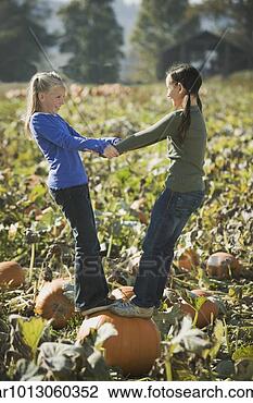 Stock Photo - two girls standing 
on pumpkin in 
pumpkin patch. 
fotosearch - search 
stock photos, 
pictures, images, 
and photo clipart