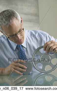 Picture - middle-aged businessman 
examining gear 
wheels. fotosearch 
- search stock 
photos, pictures, 
images, and photo 
clipart