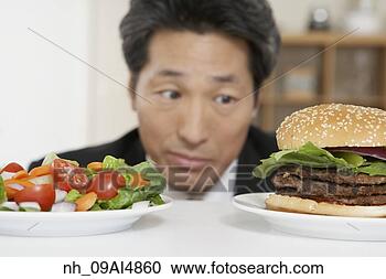 Stock Photography - asian man looking 
at salad and hamburger. 
fotosearch - search 
stock photos, 
pictures, images, 
and photo clipart