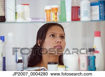 Stock Photography - hispanic woman 
looking in medicine 
cabinet. fotosearch 
- search stock 
photos, pictures, 
images, and photo 
clipart