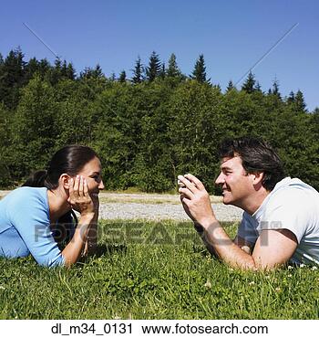 Stock Photography - man taking photograph 
of girlfriend 
in grass. fotosearch 
- search stock 
photos, pictures, 
images, and photo 
clipart