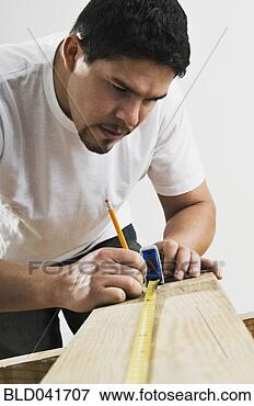 Picture - hispanic man using 
tape measure on 
wood board. fotosearch 
- search stock 
photos, pictures, 
images, and photo 
clipart