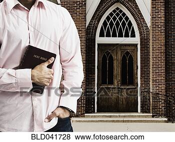 Stock Photo - mixed race man 
holding the bible 
in front of church. 
fotosearch - search 
stock photos, 
pictures, images, 
and photo clipart